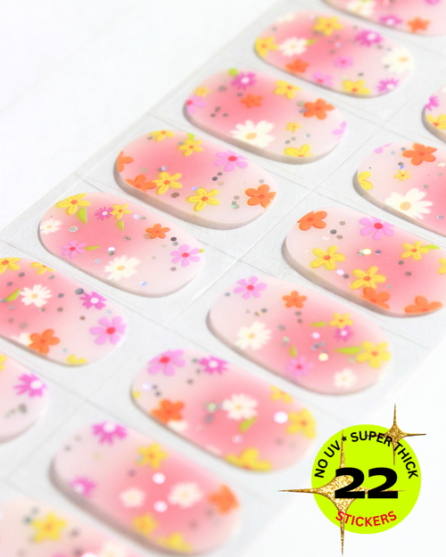 Sheet of pink gradient nail wrap decorated with small colorful flowers and glitter accents