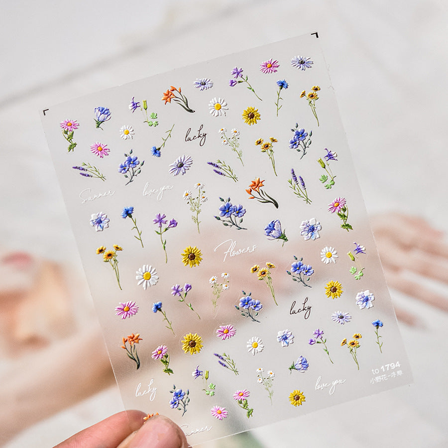 Sheet of small floral stickers held by hand on a light background