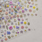 Collection of colorful floral stickers on a clear sheet with a light background