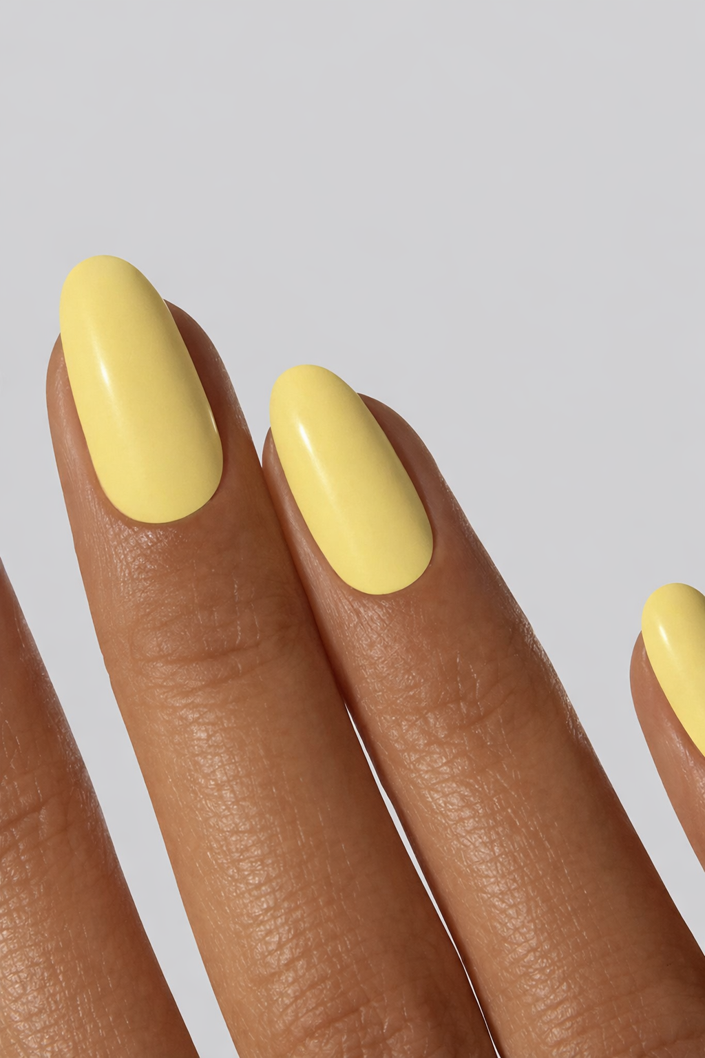 Close-up of hand with solid pastel yellow nail wraps”