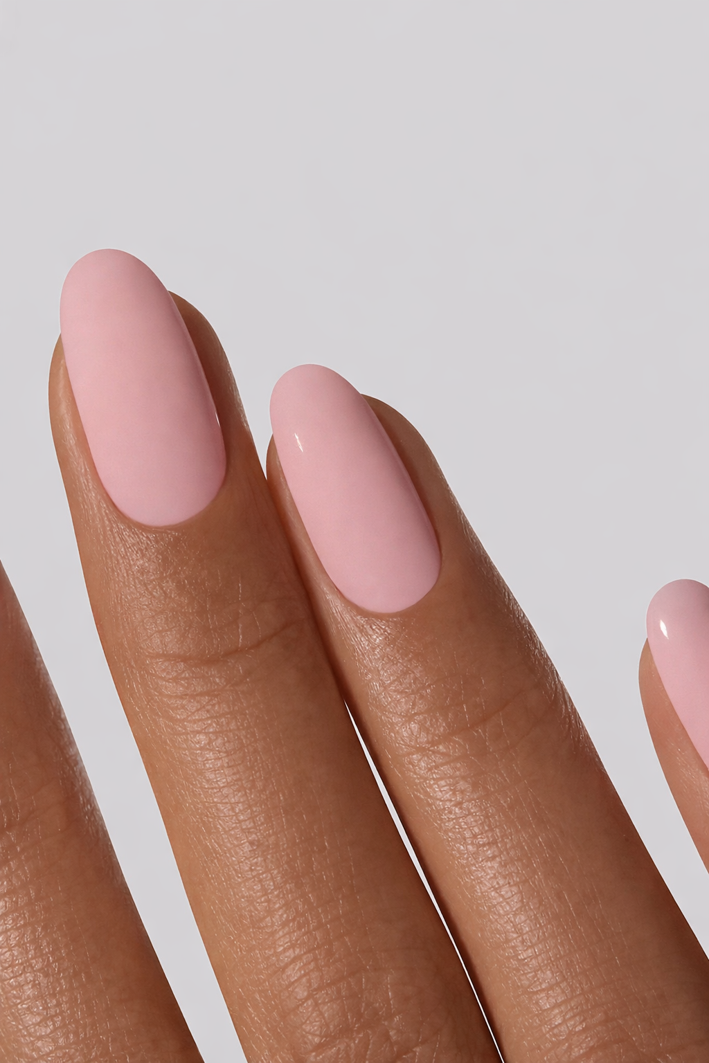 Close-up of a hand with pink nail wrap on a light gray background