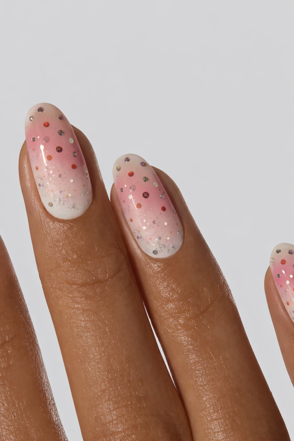 Nail wrap with pink and white polka dots on a neutral background