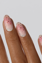 Nail wrap with pink and white polka dots on a neutral background