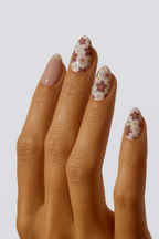 Hand with floral nail design on a plain background