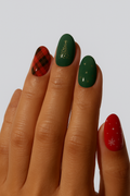 Hand with green and red nail wrap on a plain background