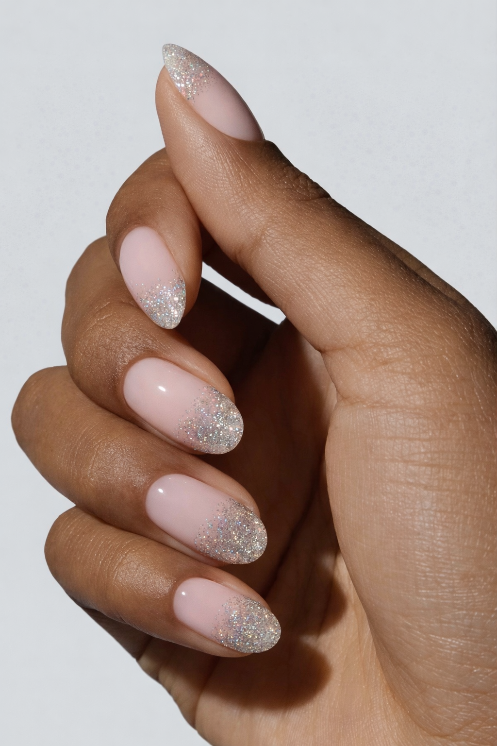 Hand with pink nails and glittery accents on a neutral background