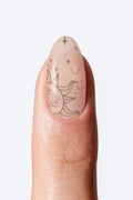 Sheer nude nail wrap manicure with delicate sun and star art.