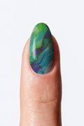 A fingernail with a green and blue nail wrap.