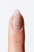 A close-up image of a single finger displaying a nail wrap with a floral design.