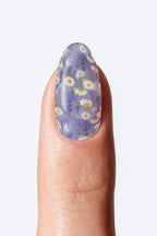 Nail with purple floral design on a light gray background