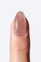 Nail with nude-colored nail wrap on a light background