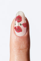 Close-up of nail with white base and small red flower artwork