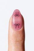 Pink gradient nail wrap with black bow design”