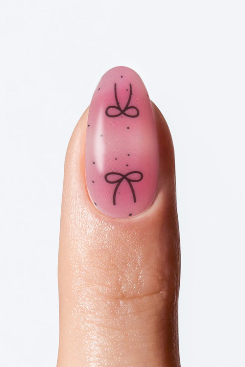 Pink gradient nail wrap with black bow design”