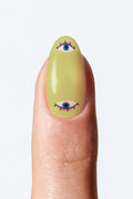 Finger with green nail art featuring eyes on a white background