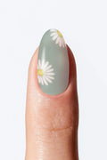 A fingernail with a green ombré nail wrap featuring flower design at the tip.