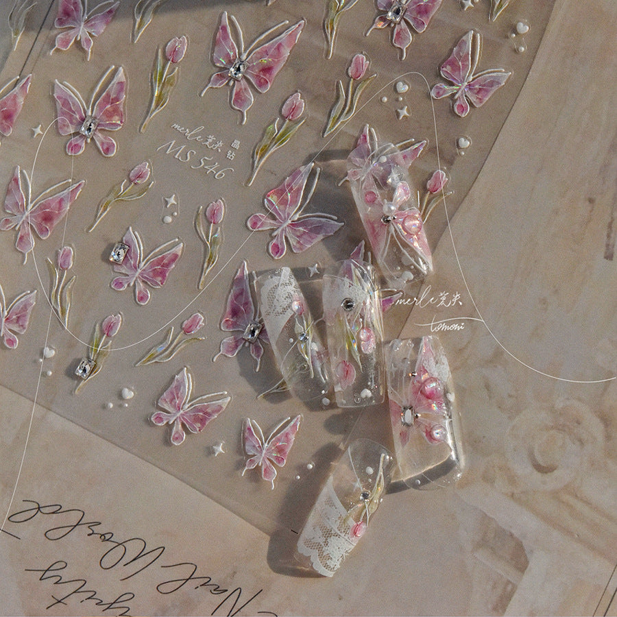 “Pink 3D butterfly nail art stickers shown with decorated sample nails featuring rhinestones and floral details.”