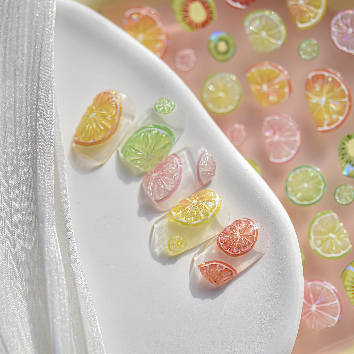 “3D citrus fruit nail art charms applied on clear sample nails, colourful summer nail decoration.”