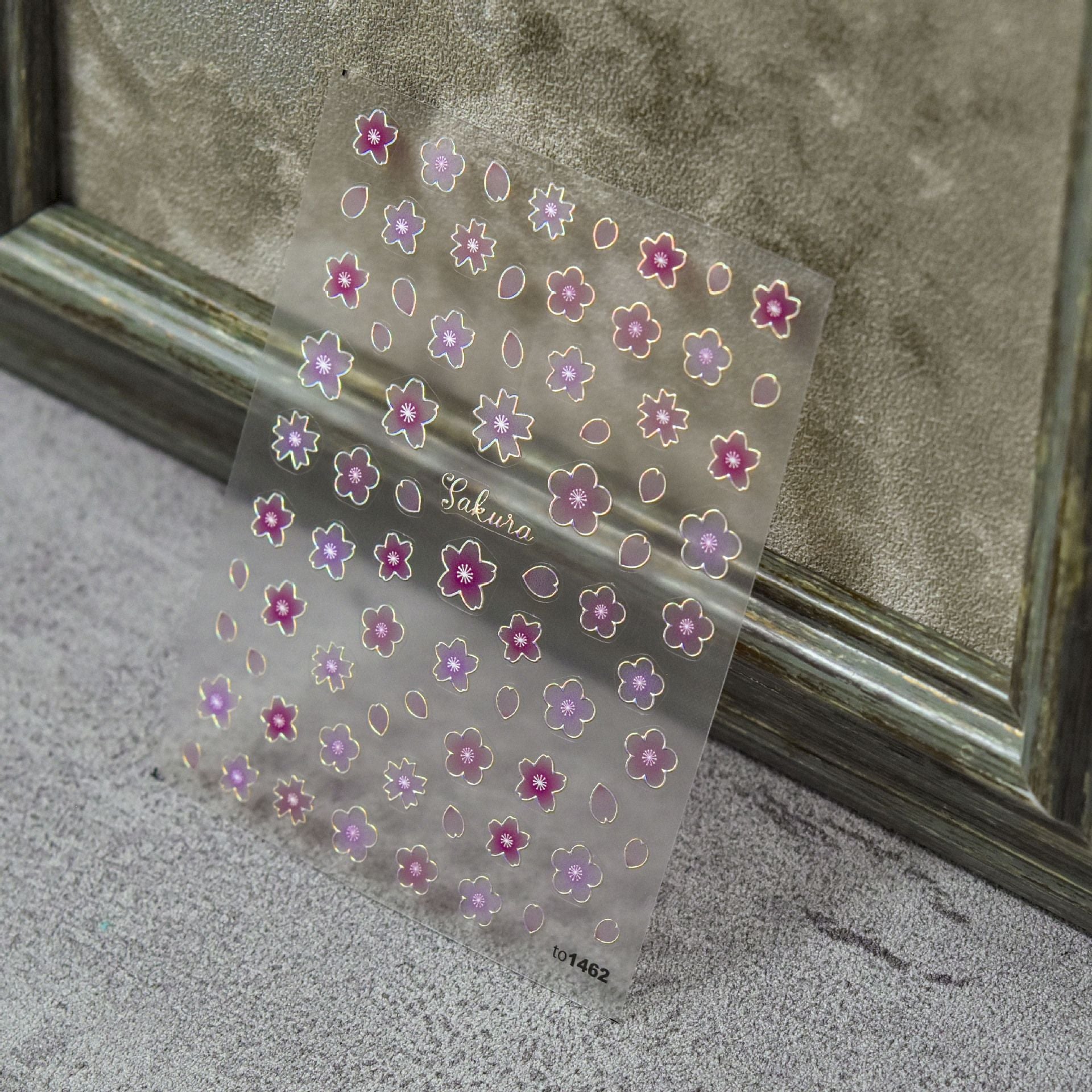 Transparent sheet of pink and purple sakura flower nail art stickers with gold outline.
