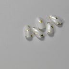 A set of golden metallic hearts  nail art stickers applied on a white nail on a light background.