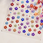A sheet of nail stickers featuring various colorful glitter flowers designed.