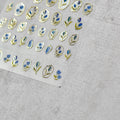 A sheet of nail stickers featuring gold and blue glitter flowers designed.