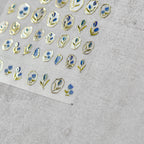 A sheet of nail stickers featuring gold and blue glitter flowers designed.