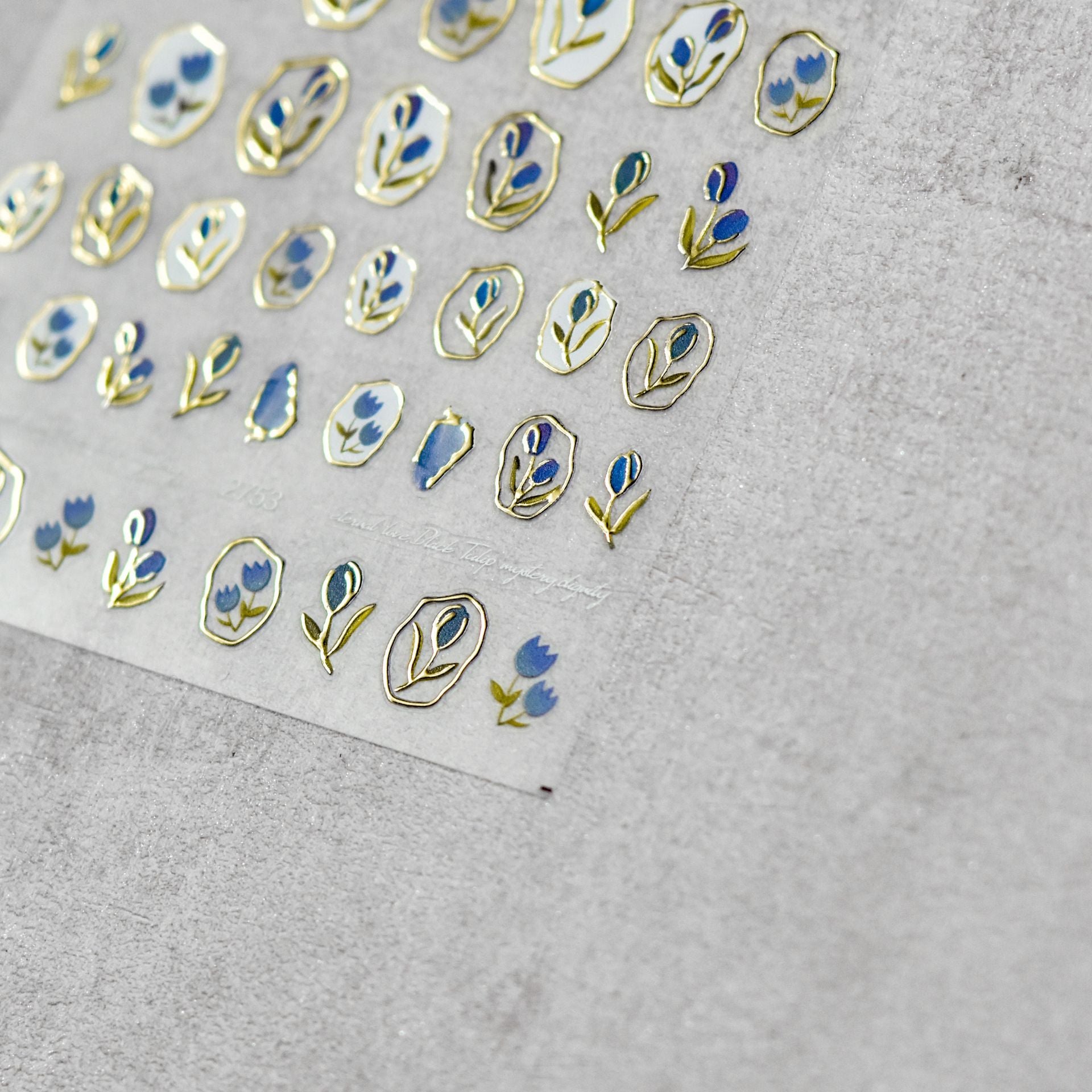 A sheet of nail stickers featuring gold and blue glitter flowers designed.
