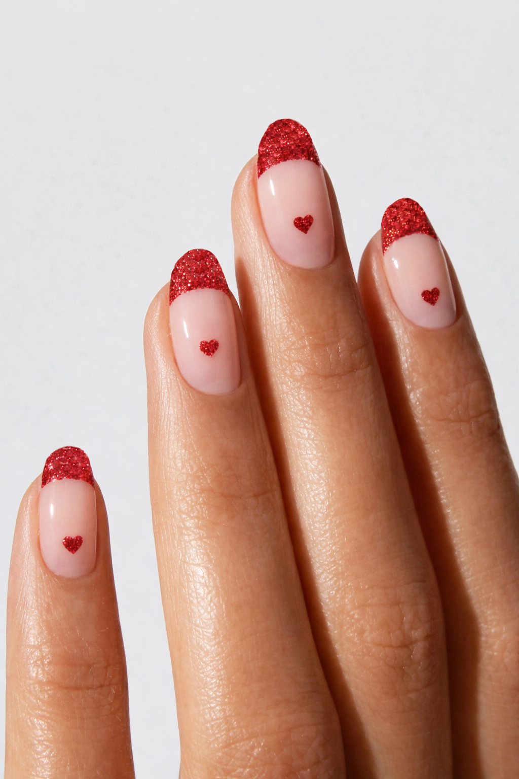 Nails with red glitter hearts on a light background
