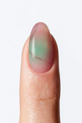 A close-up image of a fingernail wrap with a marble-like design, with a fine gold line detailing.