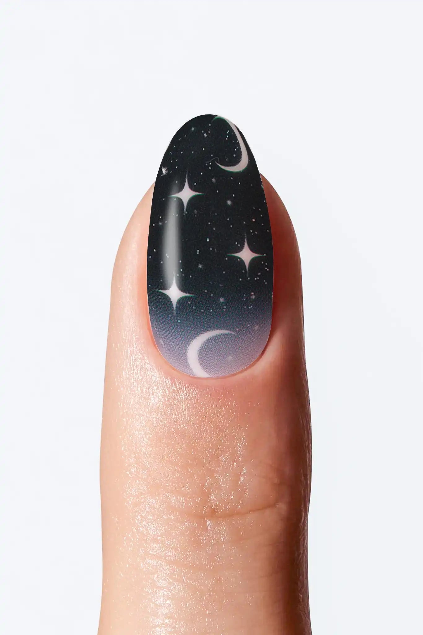 Black  nail wrap manicure with white crescent moon and star details on white background.