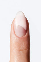 Minimal nude nail wrap manicure with soft white tip and fine silver line detail.